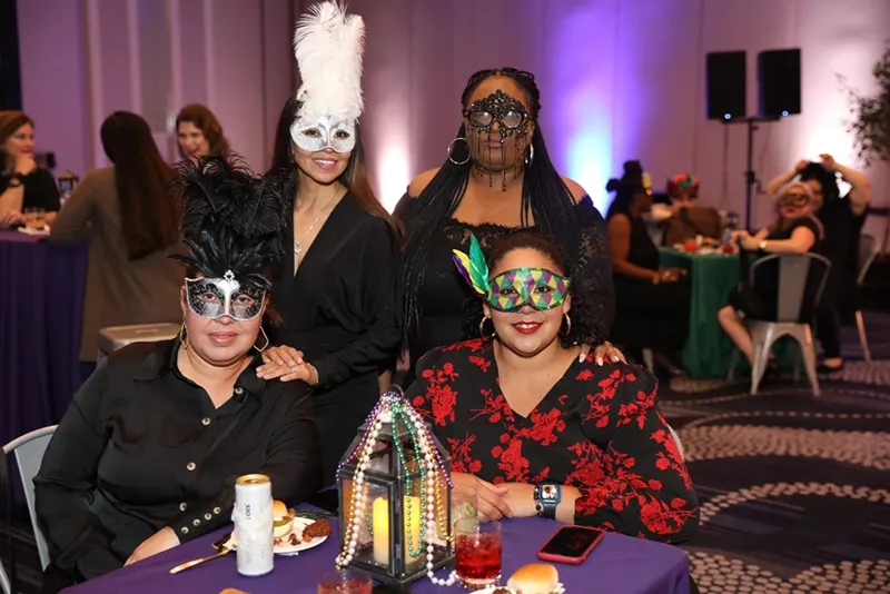 Masked conference attendees sit at a table