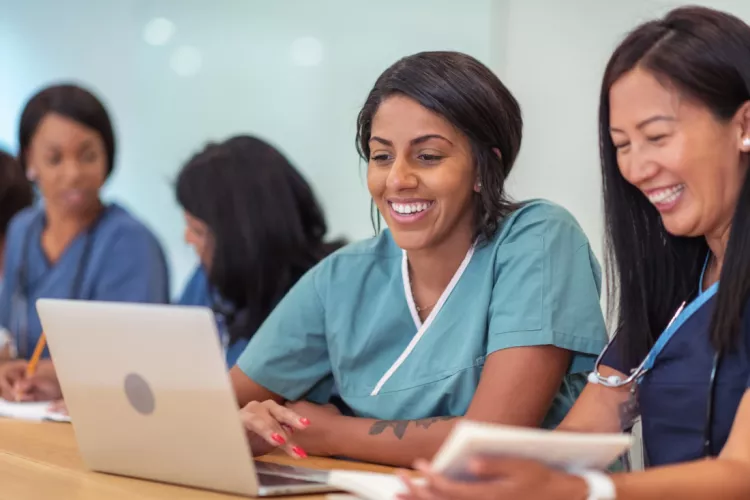 Nursing students smiling and looking at laptop